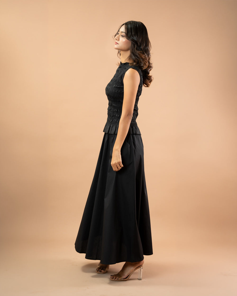 Woman wearing a black sleeveless dress against a beige background