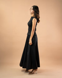 Woman wearing a black sleeveless dress against a beige background