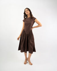Woman wearing brown boat neck midi dress, styled editorial shot